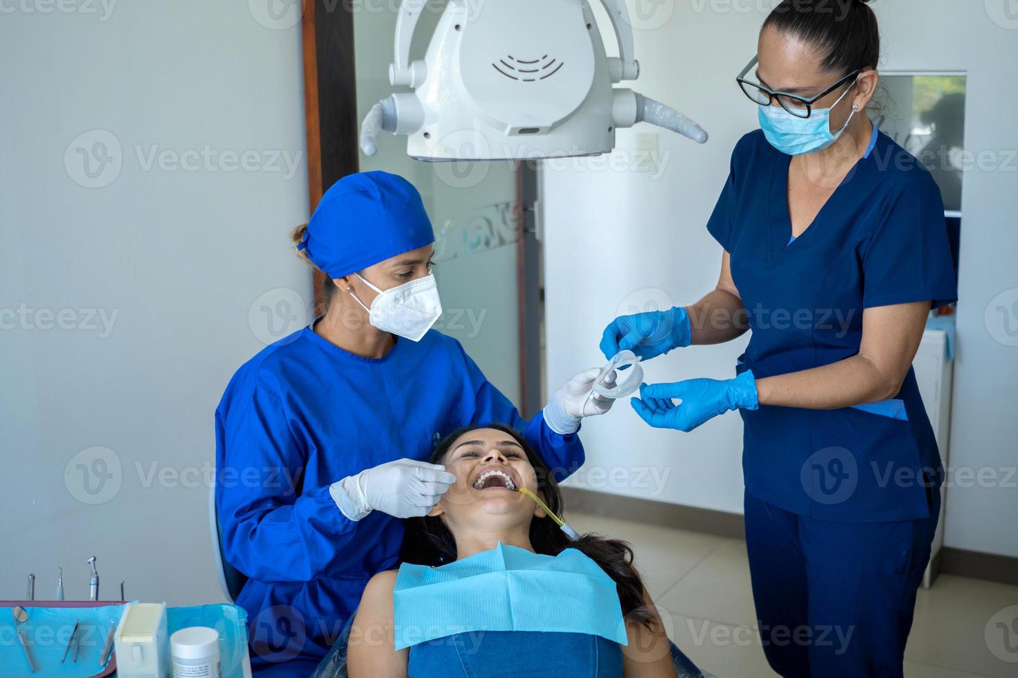 jovem dentista feminina e assistente feminina atendendo ao paciente. foto