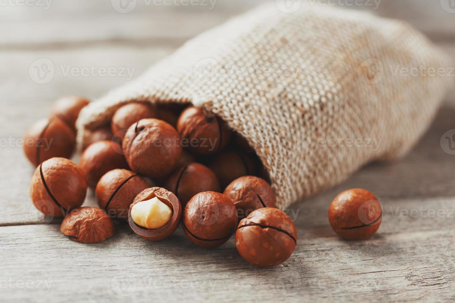 noz de macadâmia em uma mesa de madeira em um saco, closeup, vista superior foto