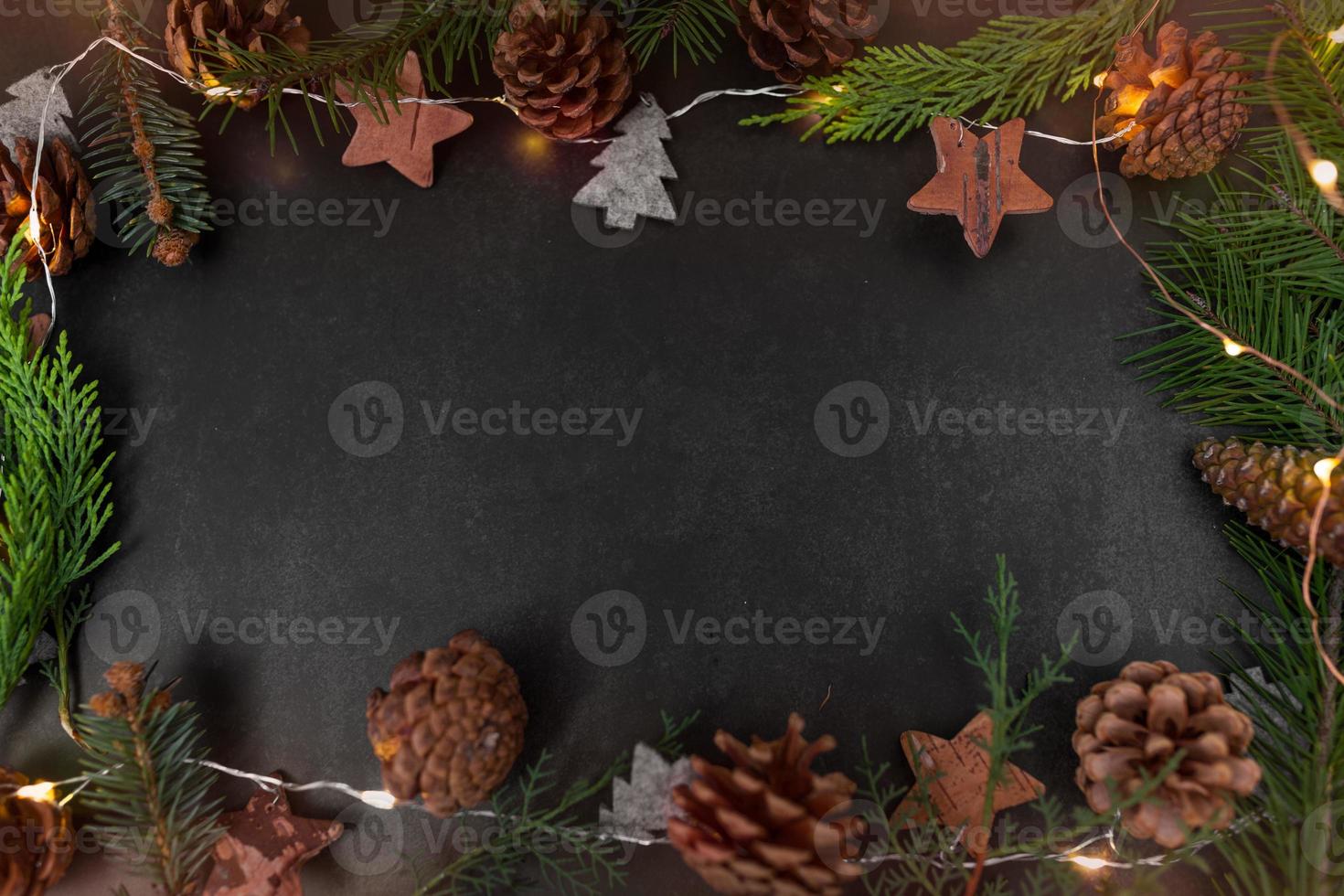 fundo escuro de natal ou ano novo com ramos de abeto, placa preta de natal emoldurada com decorações de temporada, espaço para texto, vista de cima. foto