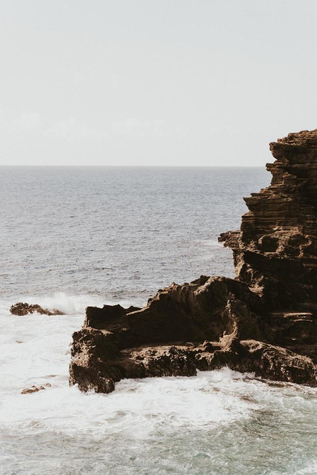 formação de rocha marrom no mar durante o dia foto