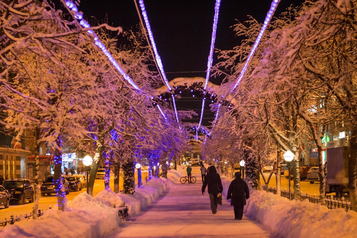 o beco festivo é decorado com luzes de guirlandas para o natal e o ano novo. decoração ao ar livre das ruas da cidade, pessoas andando. kaluga, rússia, dezembro de 2020. foto