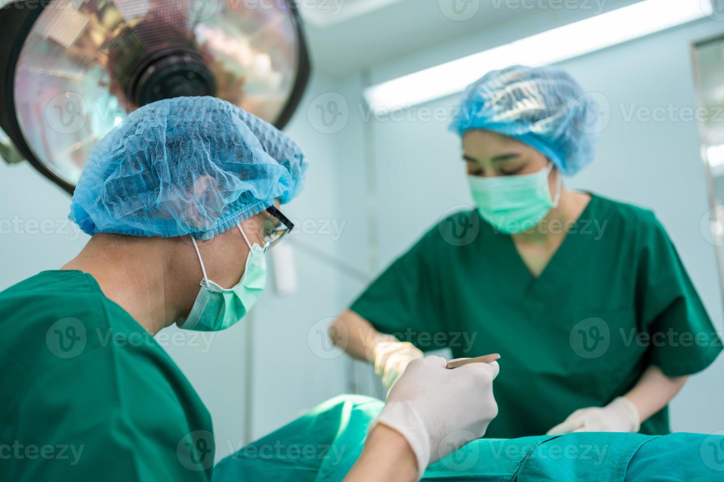 equipe de cirurgiões profissionais asiáticos realizando cirurgia na sala de cirurgia, cirurgião, assistentes e enfermeiras realizando cirurgia em um paciente, câncer de saúde e conceito de tratamento de doenças foto