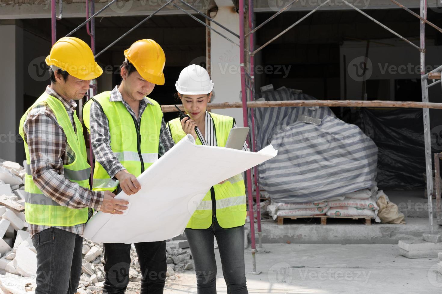 engenheira asiática ou jovem arquiteta coloca um capacete por segurança e conversa com um empreiteiro em um projeto de fábrica de construção, conceito de trabalho em equipe, conceito de liderança. foto