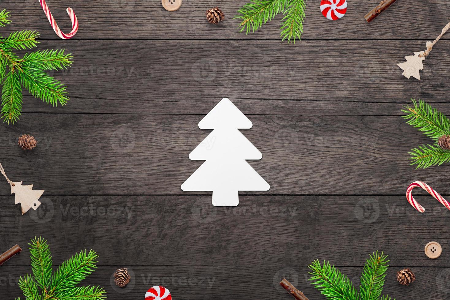 linda árvore de natal de papel em uma mesa de madeira cercada por decorações de natal. cartão de feliz natal com espaço de cópia foto