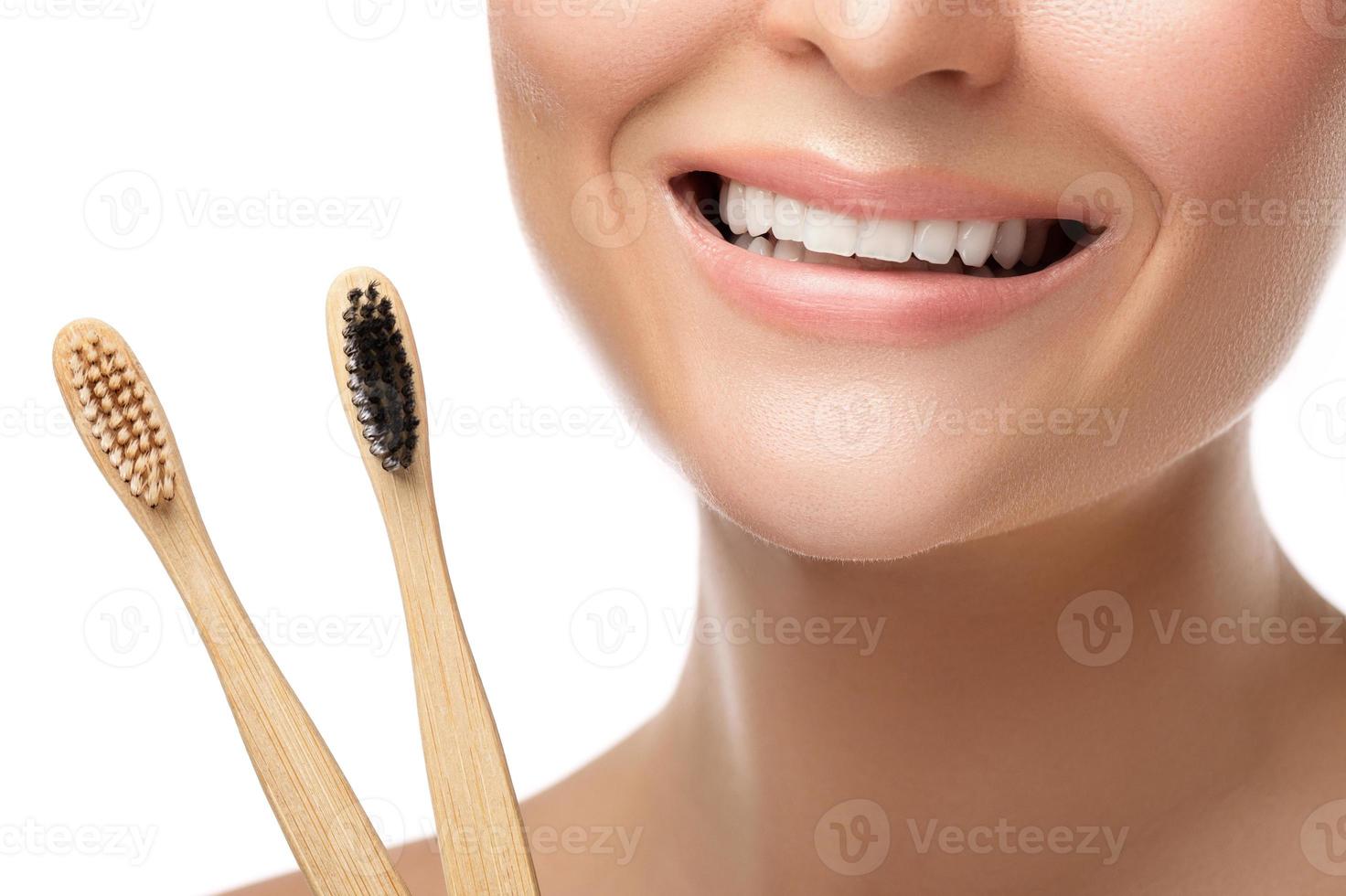 boca feminina com dentes brancos e escovas de dentes de bambu foto