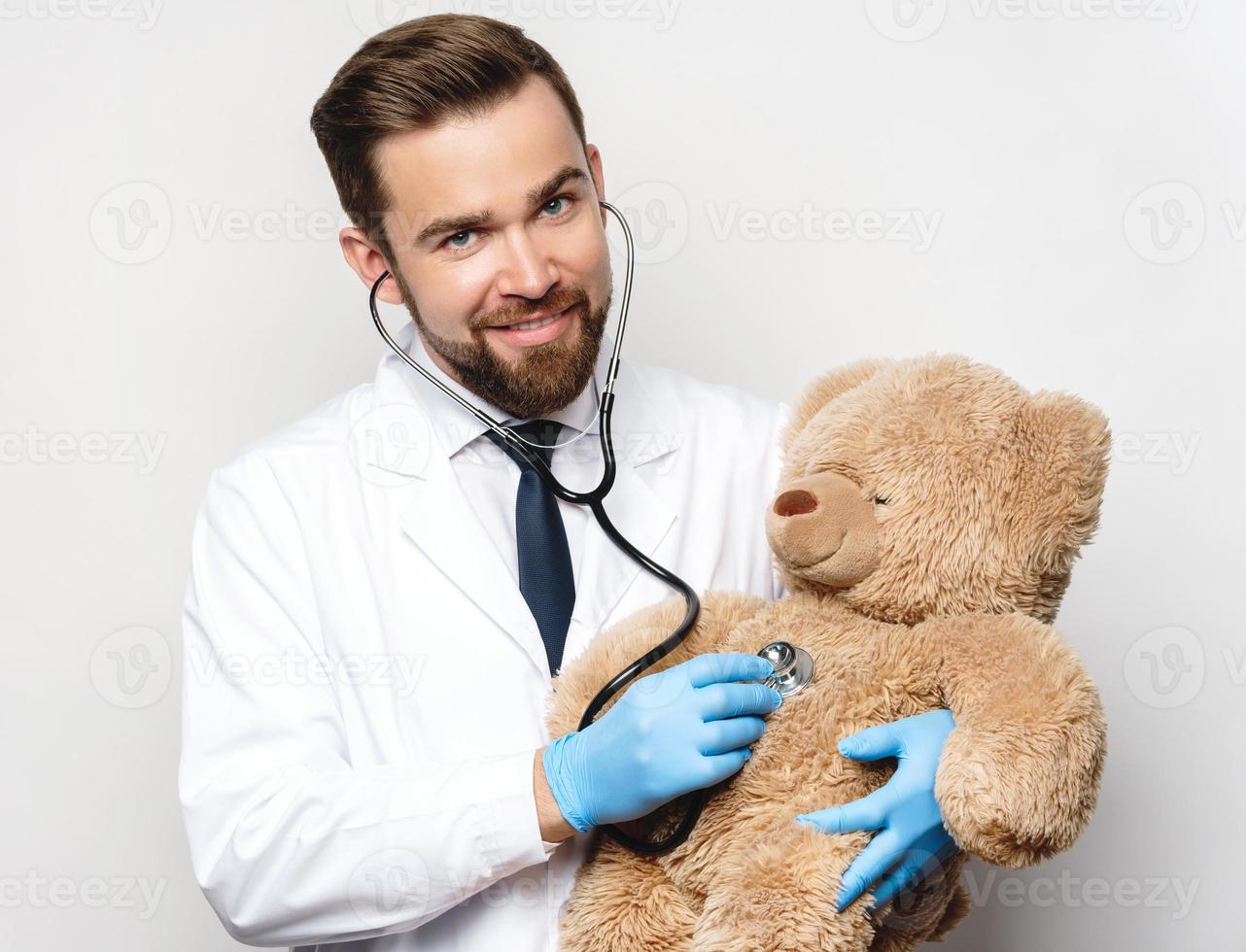 pediatra profissional com um ursinho de pelúcia nas mãos foto
