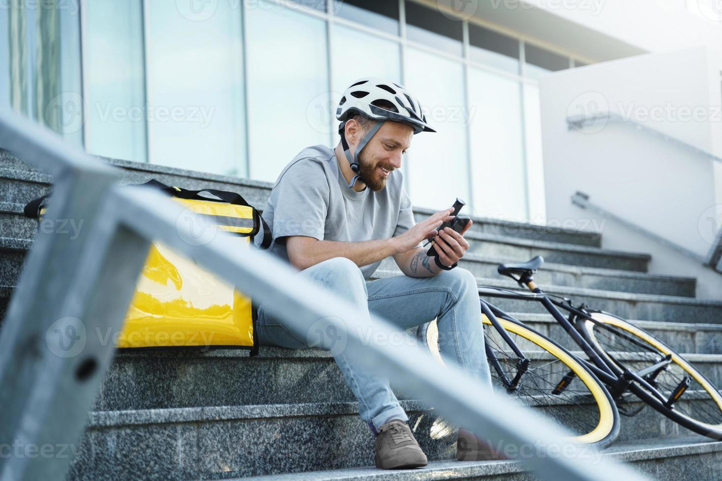 correio expresso de entrega de comida sentado na escada com bolsa isolada e bicicleta. foto