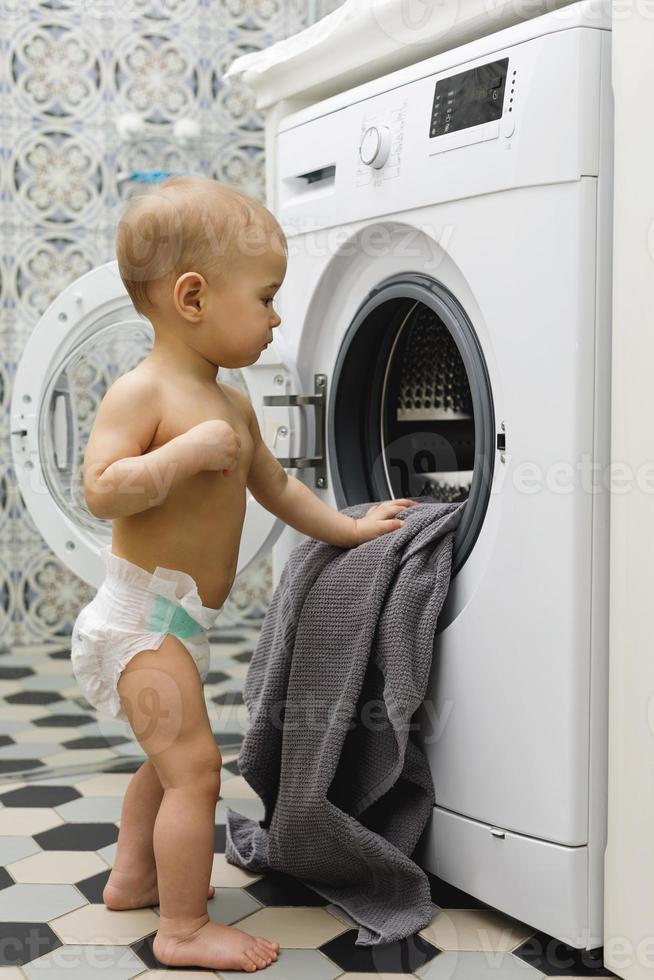 menino bonito está olhando para dentro da máquina de lavar foto