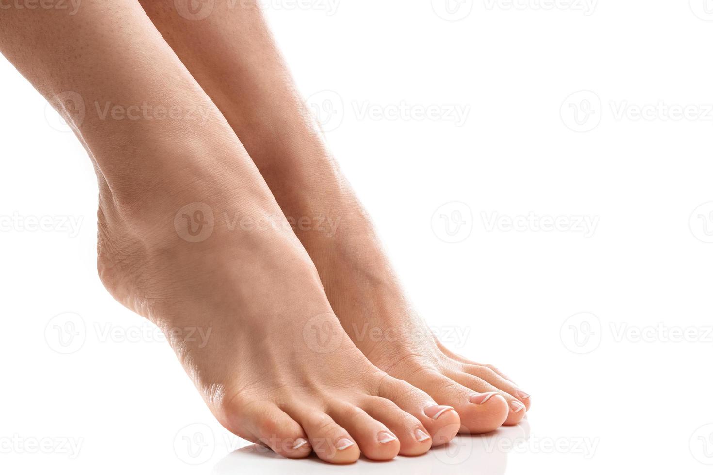 pés femininos com pele macia e pedicure francesa em fundo branco foto