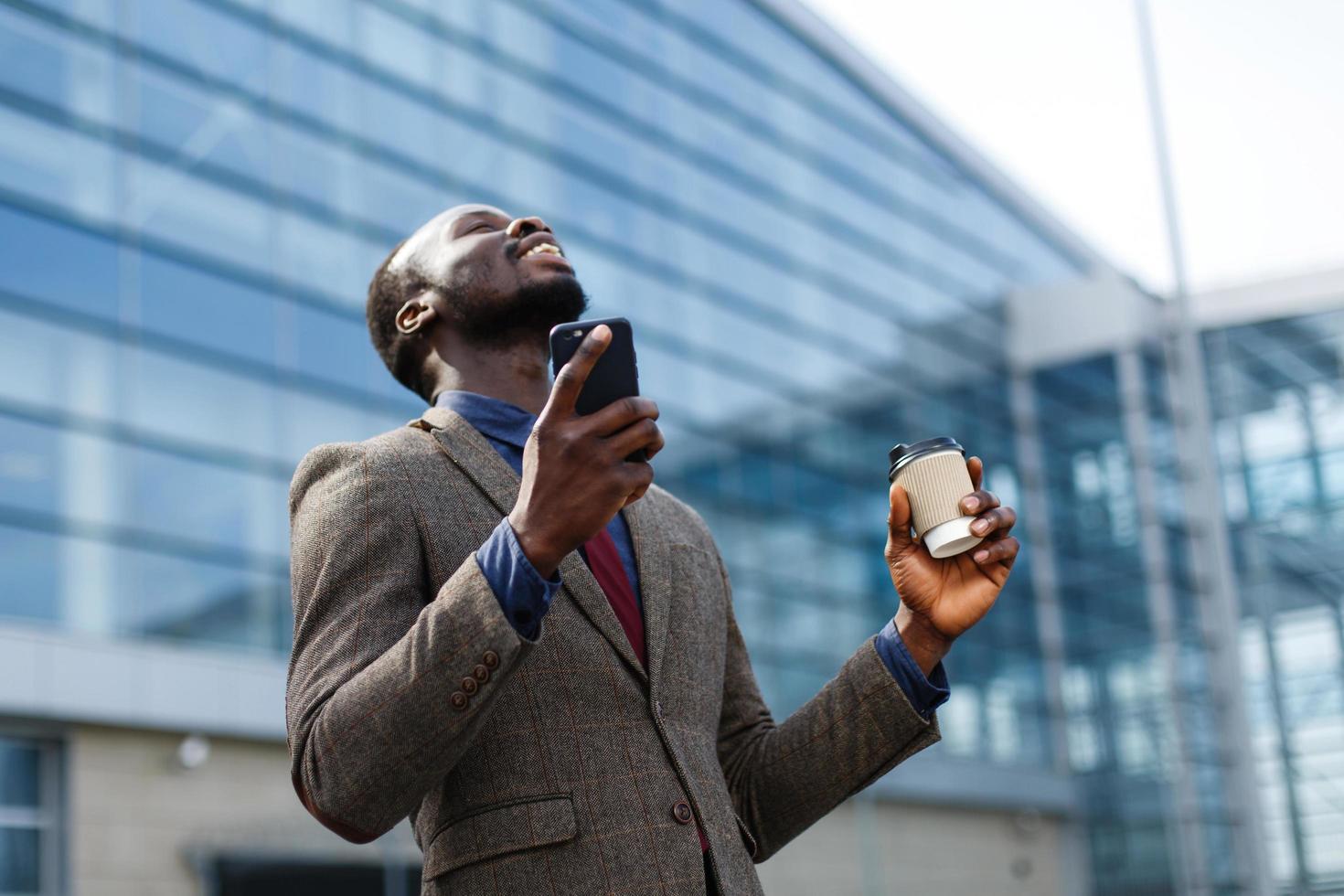 homem feliz segurando telefone e café foto