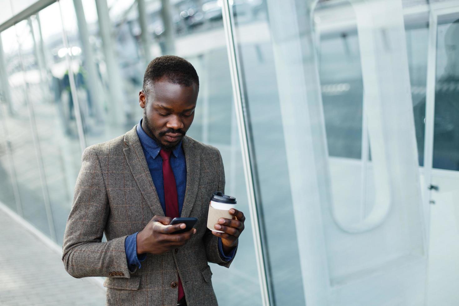 homem lendo algo em seu smartphone enquanto está do lado de fora com uma xícara de café foto