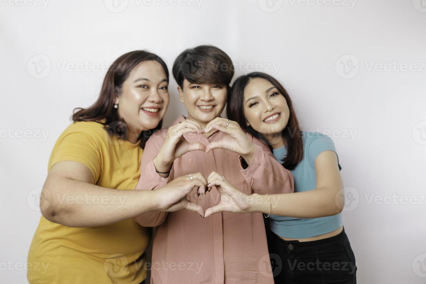 três mulheres asiáticas se sentem felizes e um gesto de coração de formas românticas expressa sentimentos ternos, conceito de amizade próxima. foto