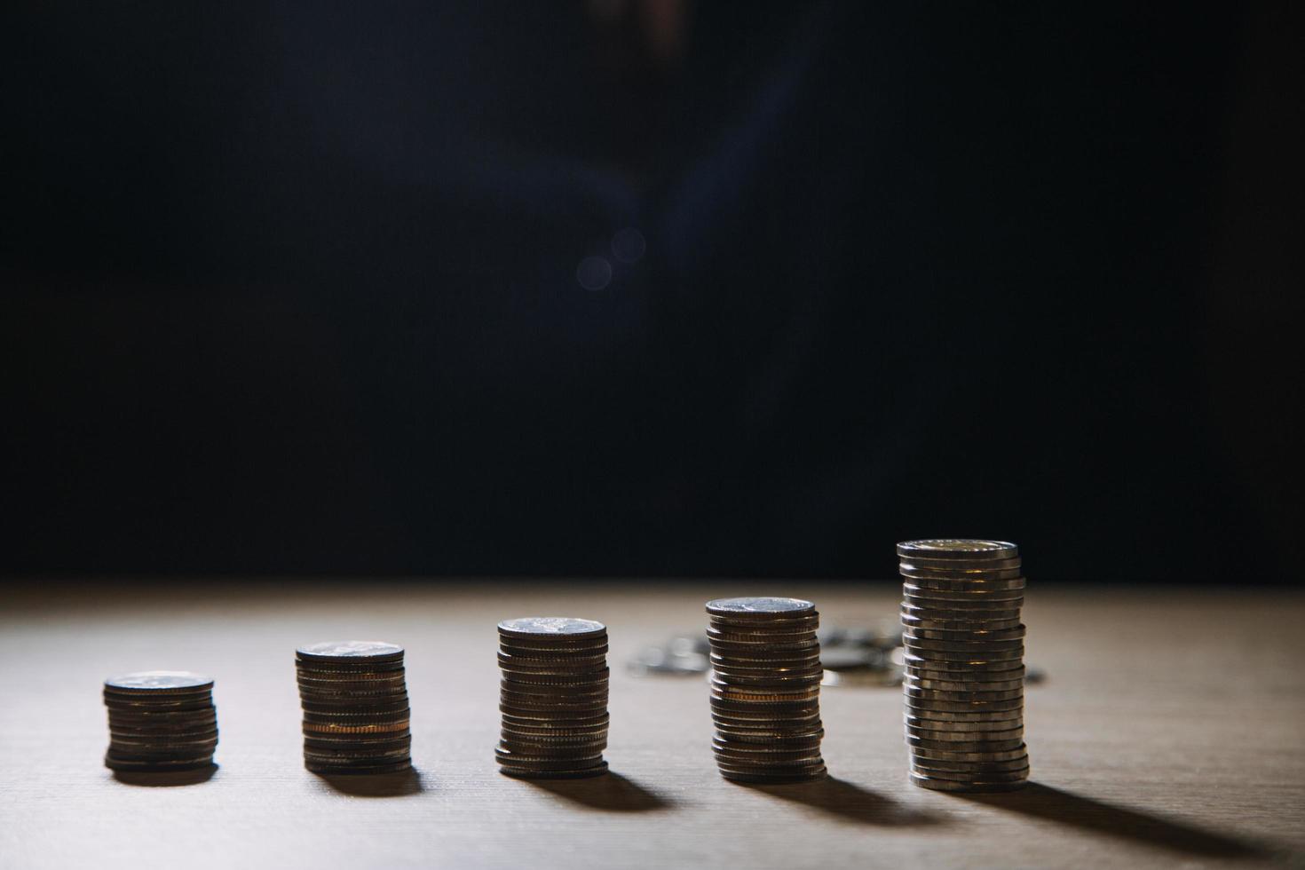 economizando dinheiro mão colocando moedas na pilha na mesa com luz do sol. conceito finanças e contabilidade foto