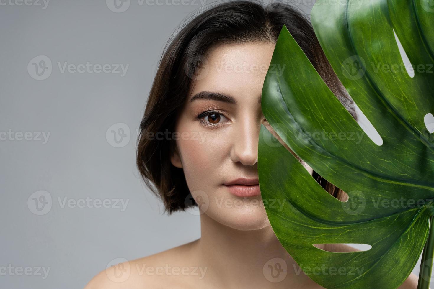 retrato de uma jovem bela morena com uma folha tropical de monstera deliciosa foto