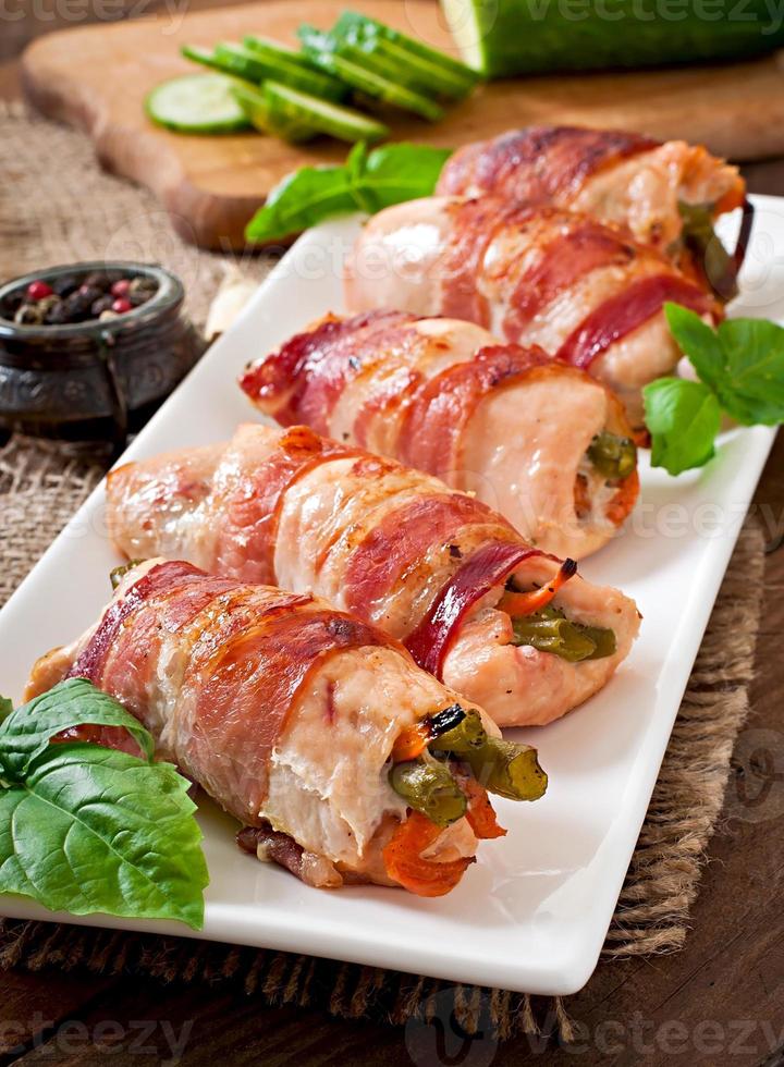 deliciosos rolinhos de frango recheados com feijão verde e cenoura envoltos em tiras de bacon foto