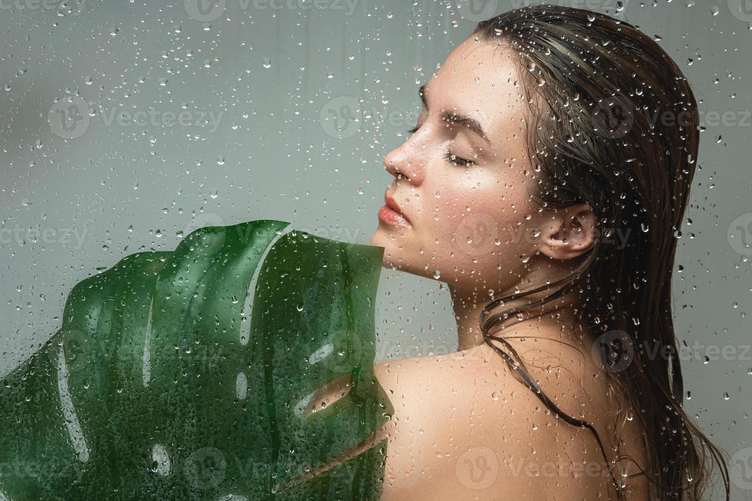 jovem mulher com uma pele lisa segurando a folha da planta monstera deliciosa foto