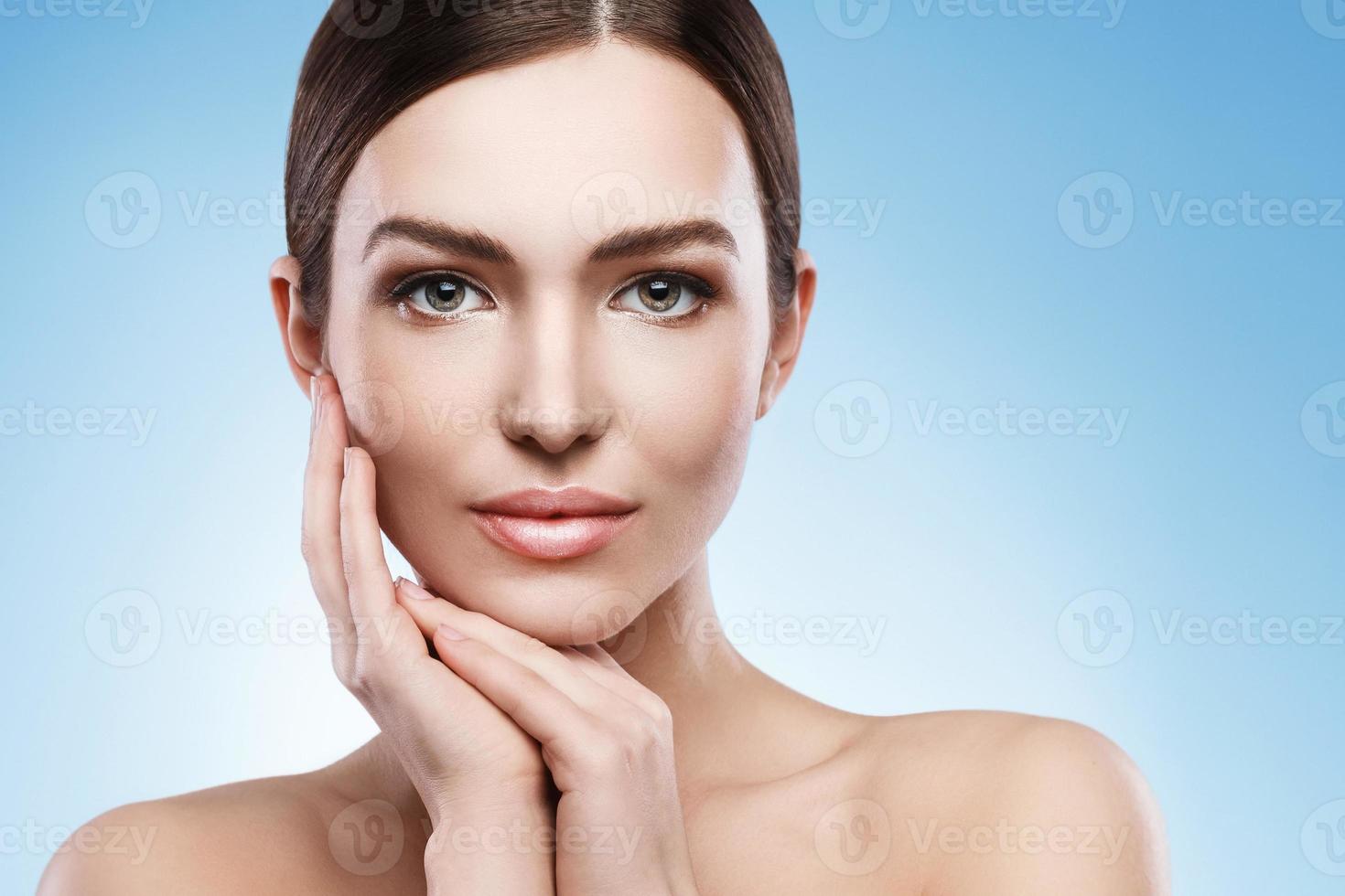 jovem mulher com maquiagem natural e pele lisa contra fundo azul claro foto