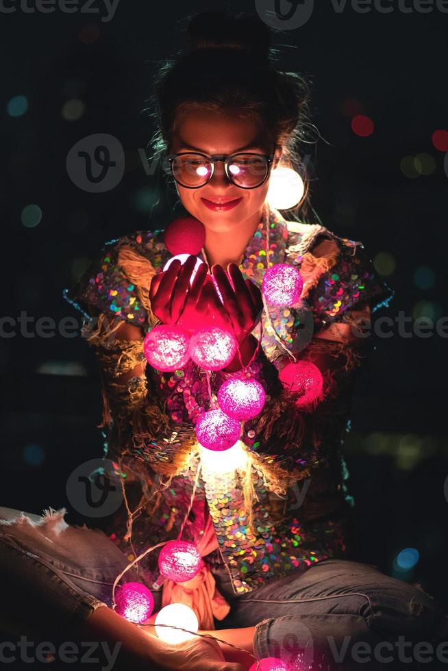 mulher feliz vestindo jaqueta brilhante com lantejoulas está segurando bolas de luz em suas mãos foto