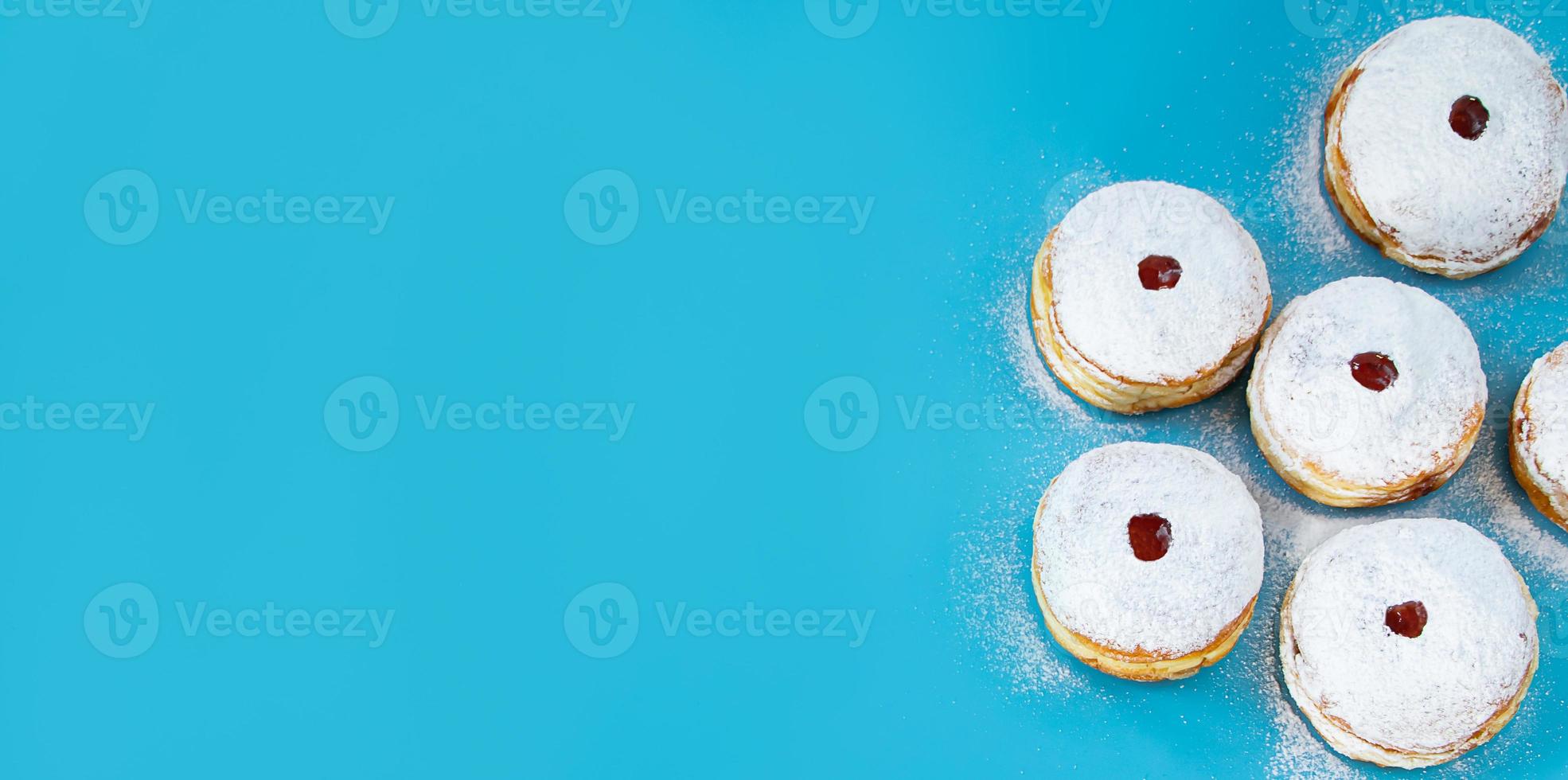 símbolos do feriado religioso judaico hanukkah. rosquinhas de sobremesa tradicional sufganiyot sobre fundo azul. foto