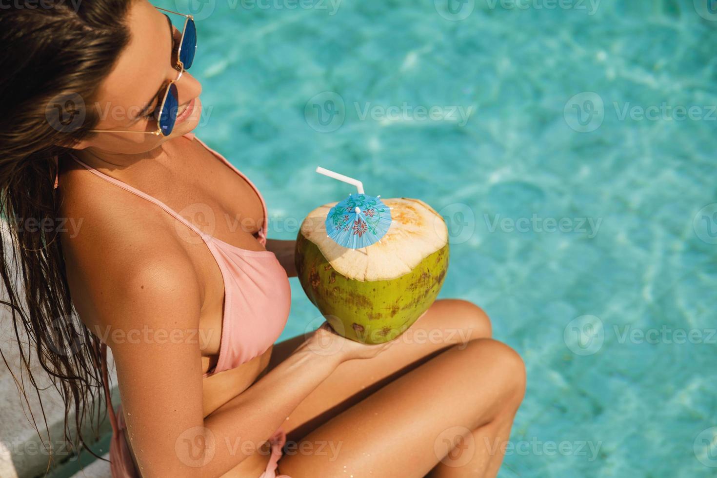 mulher relaxando na piscina e bebendo água de coco foto