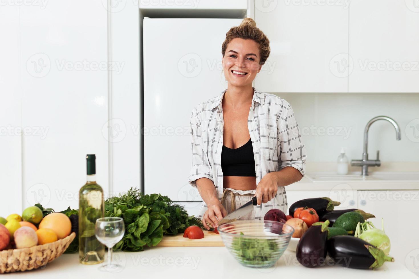 jovem mulher alegre cozinhando prato vegetariano saudável em casa foto