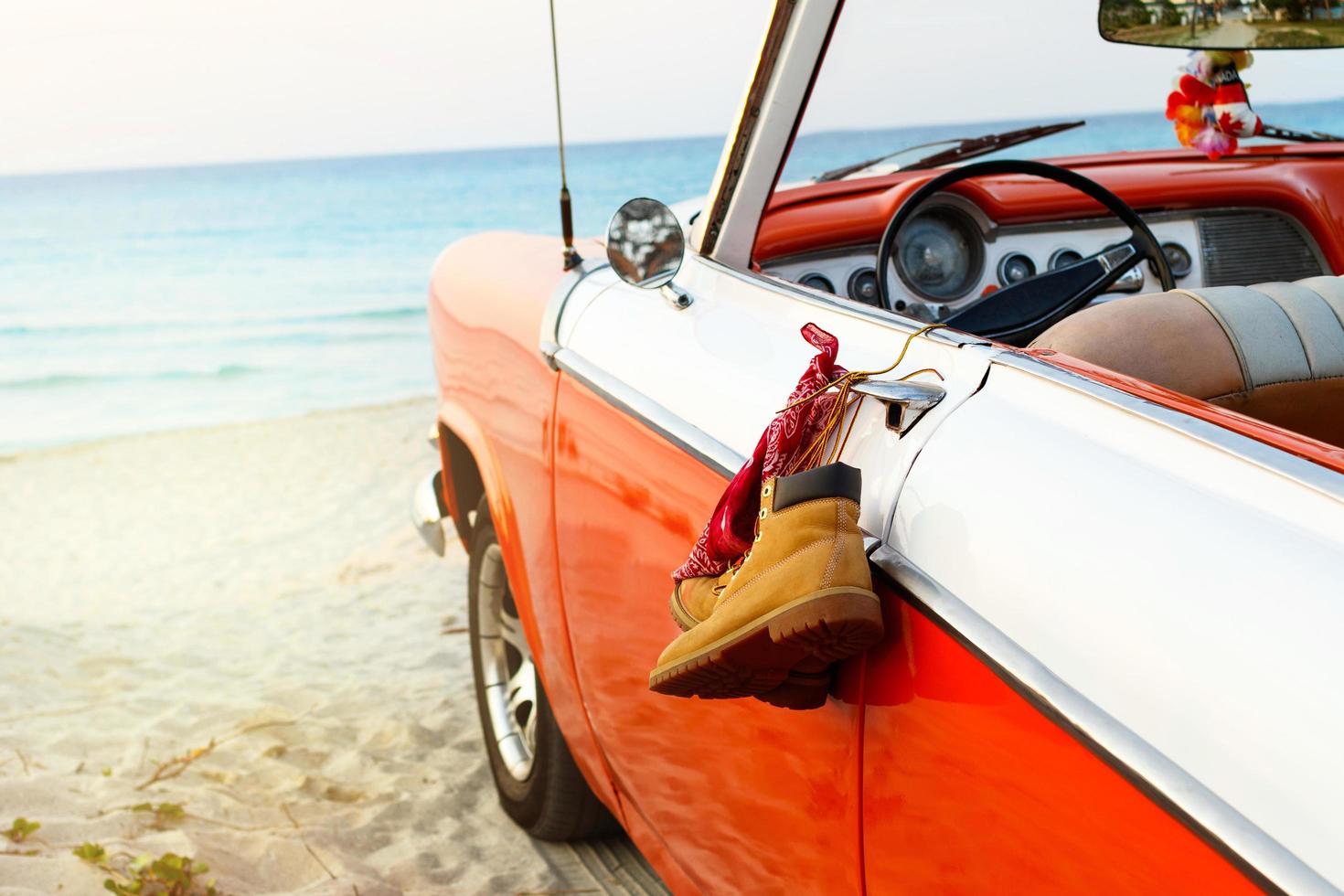carro com botas amarradas e bandana para uma maçaneta na praia foto