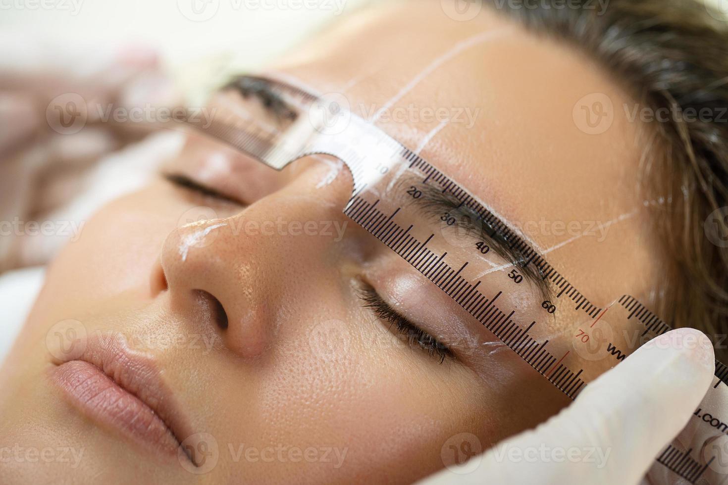 mulher durante procedimento profissional de mapeamento de sobrancelha foto