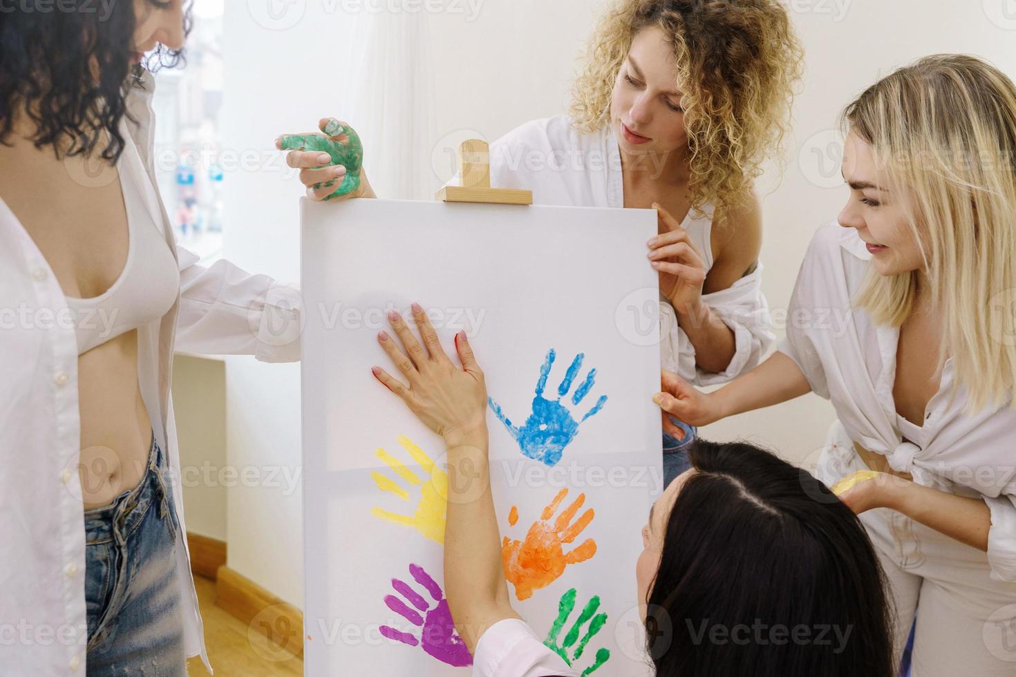 grupo de mulheres pintando em tela e bebendo vinho branco durante festa em casa foto