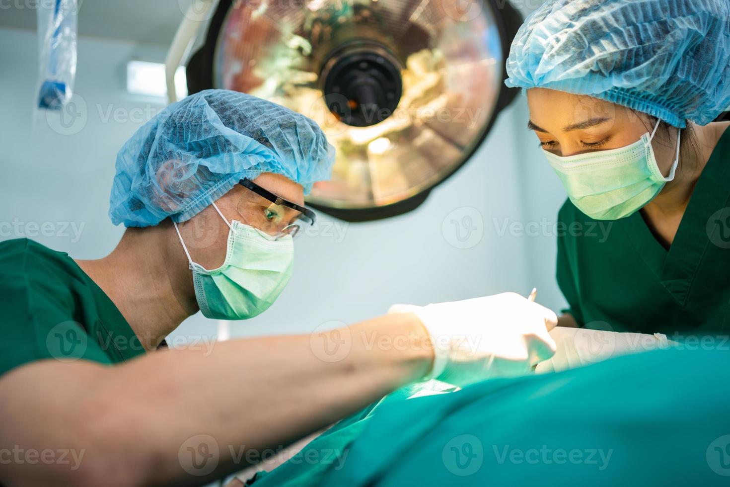 equipe de cirurgiões profissionais asiáticos realizando cirurgia na sala de cirurgia, cirurgião, assistentes e enfermeiras realizando cirurgia em um paciente, câncer de saúde e conceito de tratamento de doenças foto