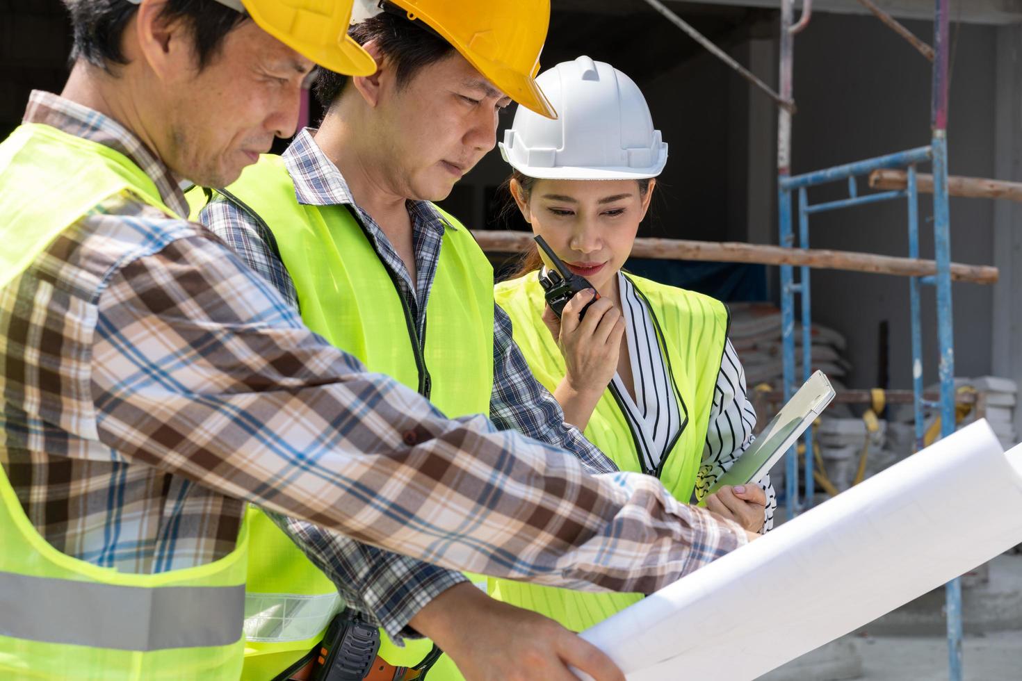 engenheira asiática ou jovem arquiteta coloca um capacete por segurança e conversa com um empreiteiro em um projeto de fábrica de construção, conceito de trabalho em equipe, conceito de liderança. foto