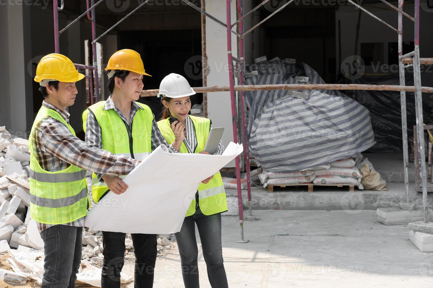 engenheira asiática ou jovem arquiteta coloca um capacete por segurança e conversa com um empreiteiro em um projeto de fábrica de construção, conceito de trabalho em equipe, conceito de liderança. foto