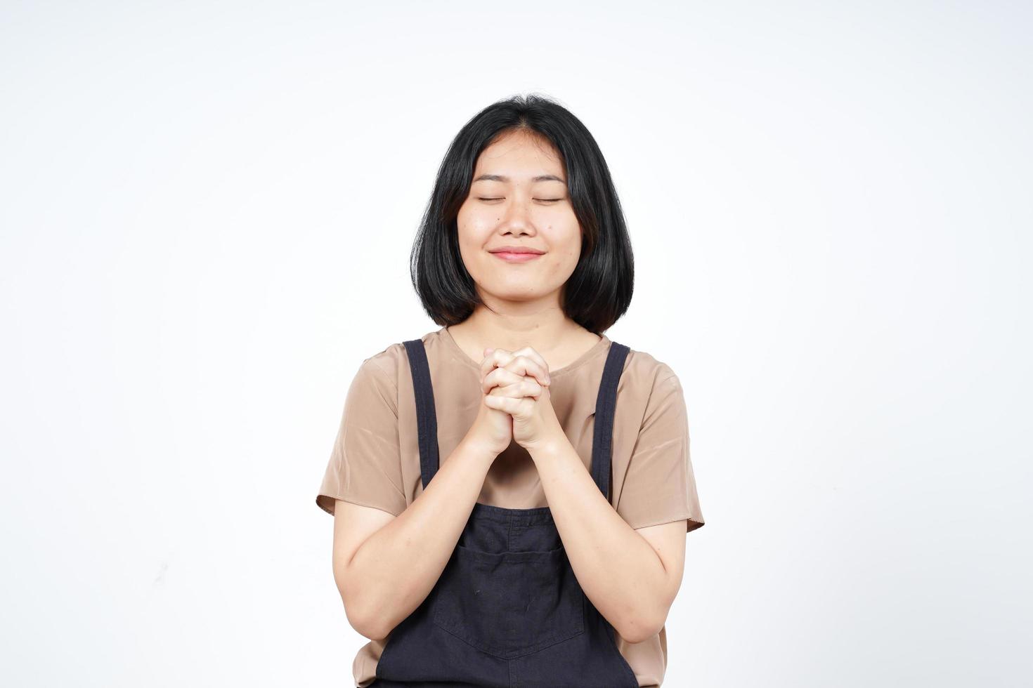 dobrando a mão fechada olho e rezar de linda mulher asiática isolada no fundo branco foto