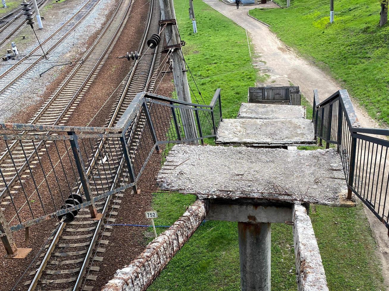 velhos degraus desmoronados de uma ponte ferroviária alta com buracos. ponte perigosa quebrada exigindo reparo e fechamento urgentes foto