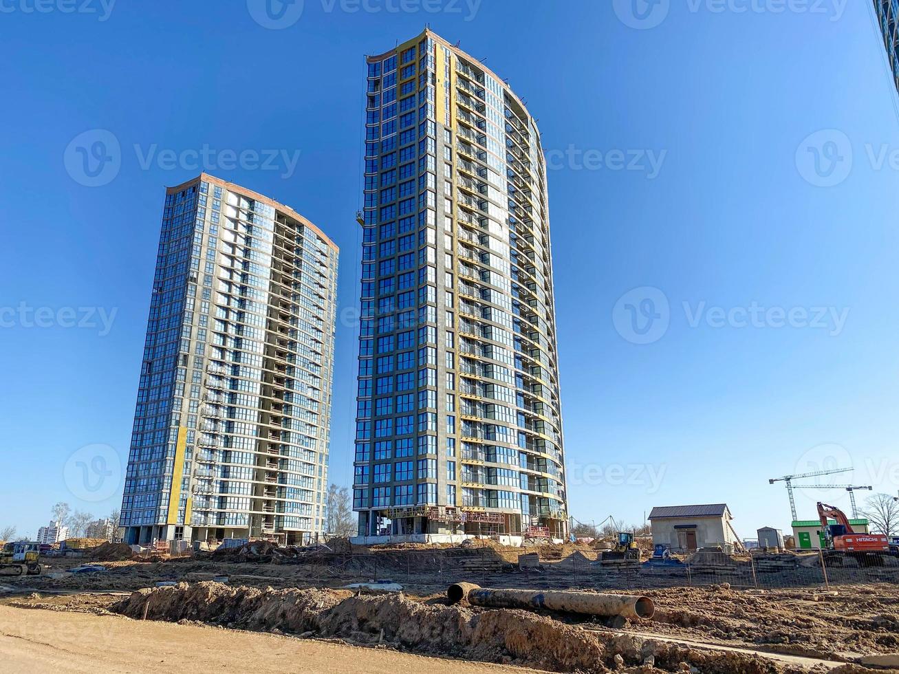 dois belos e modernos edifícios novos inacabados feitos de vidro e concreto contra um céu azul foto