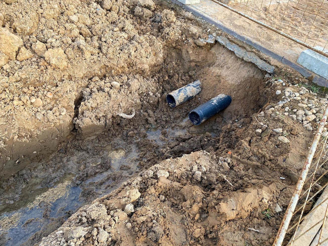 um poço escavado é uma vala para a colocação de cabos e fios com canos sob o solo durante a construção e reparo de casas na cidade da megalópole foto