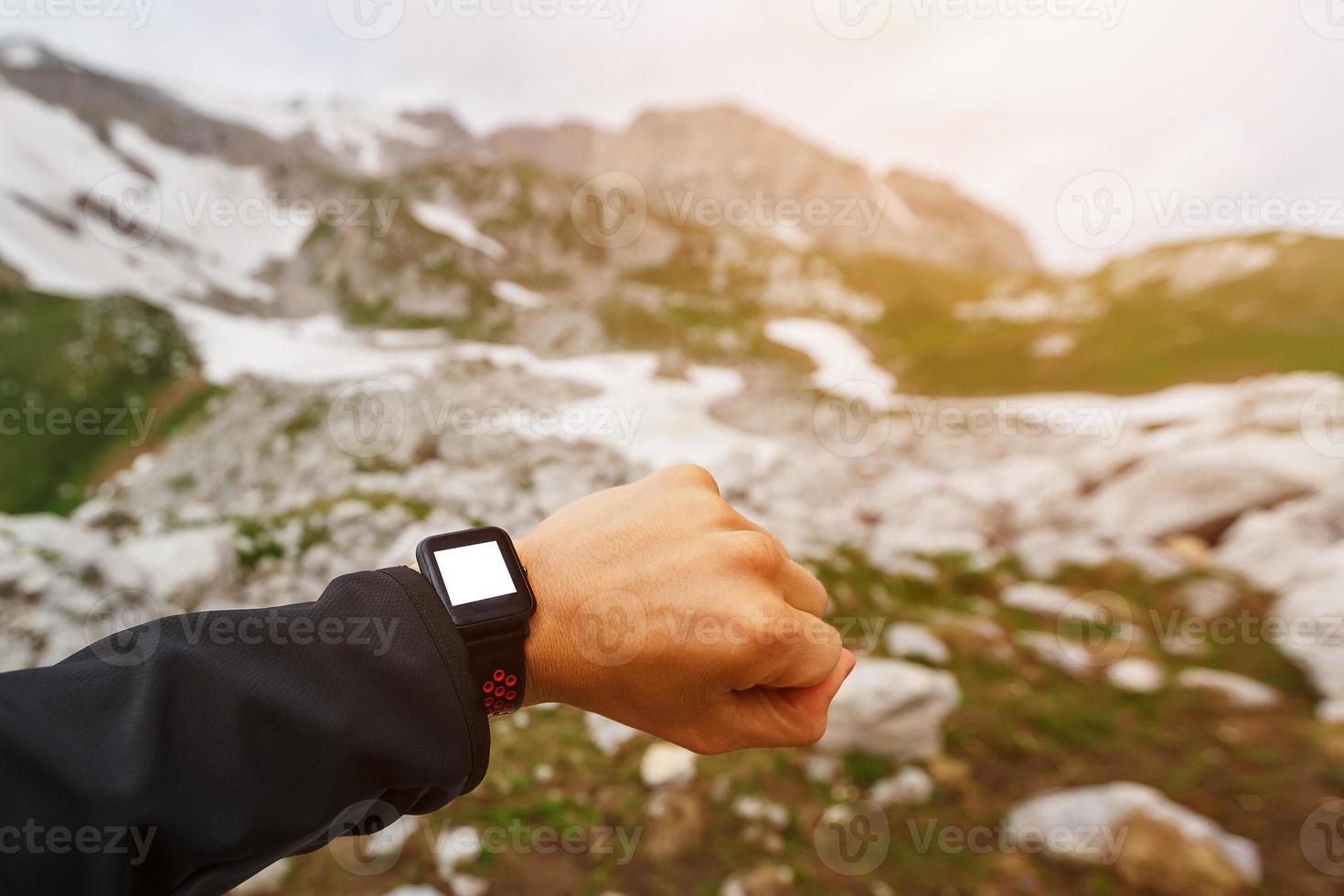 viajante de mão usando e olhando para o relógio inteligente no alto das montanhas. tecnologias modernas foto