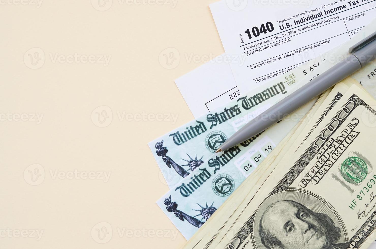 Formulário de declaração de imposto de renda individual 1040 com cheque de reembolso e notas de cem dólares em fundo bege foto