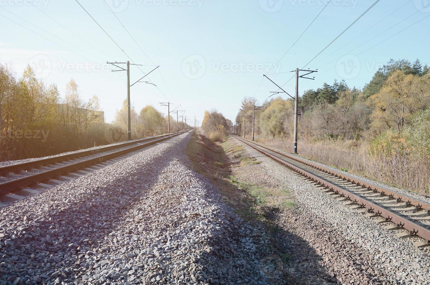 paisagem industrial de outono. ferrovia recuando na distância entre árvores de outono verdes e amarelas foto