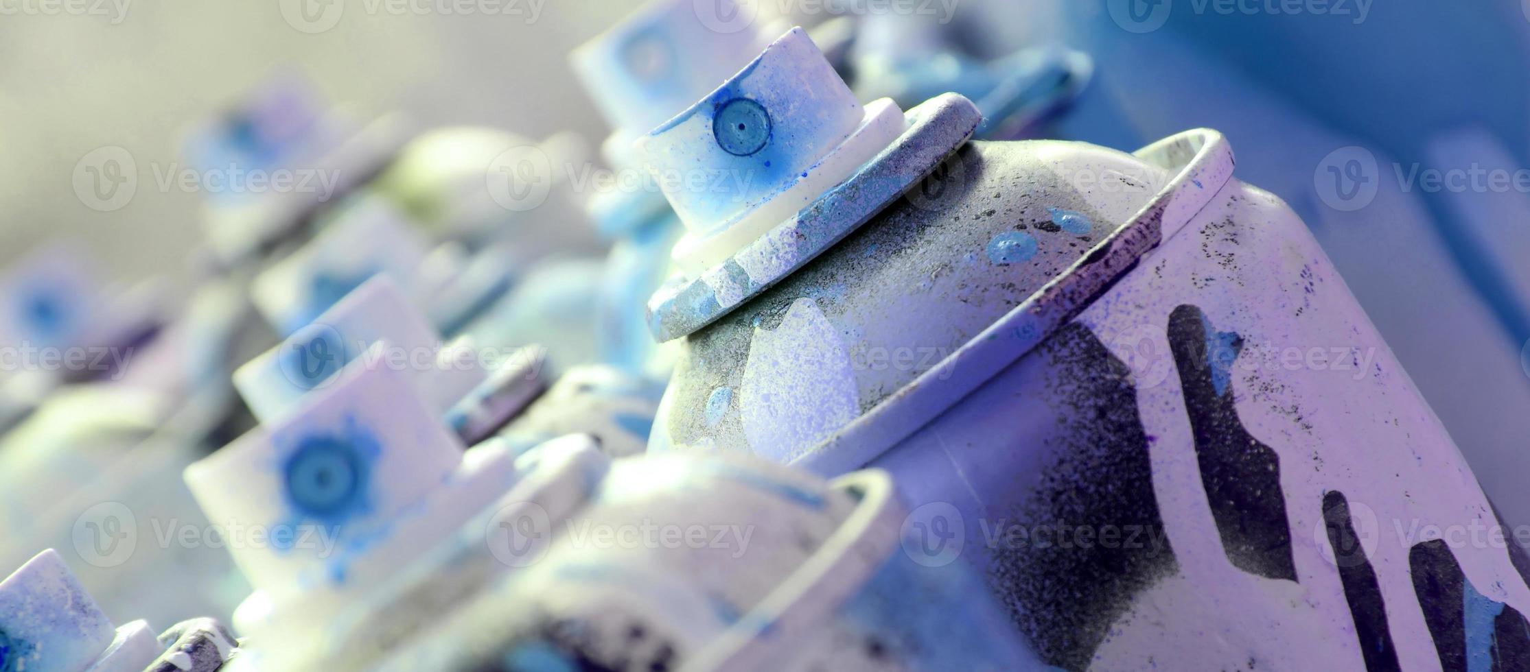 muitas latas de aerossol sujas e usadas de tinta azul brilhante. fotografia macro com profundidade de campo rasa. foco seletivo no bico de pulverização foto