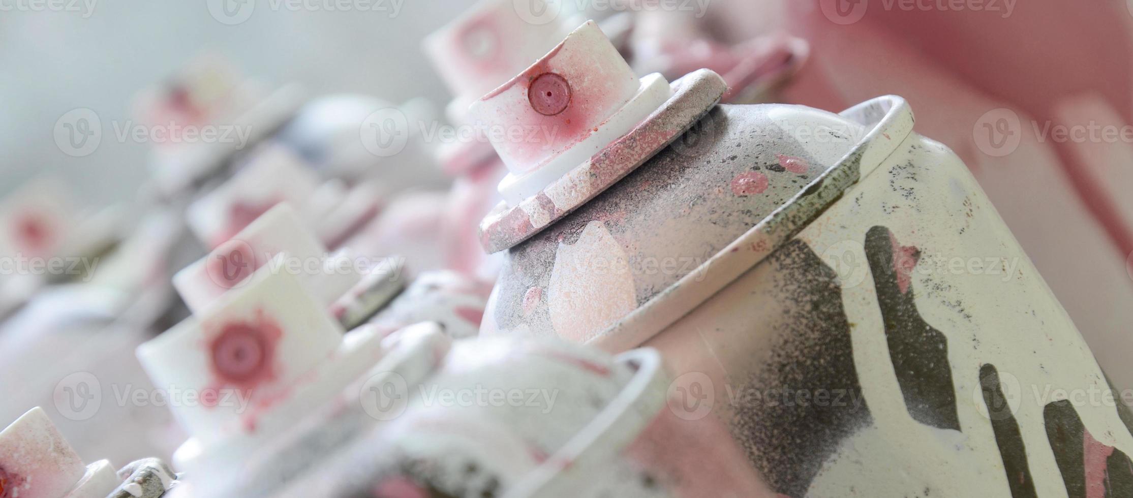 um monte de latas de aerossol sujas e usadas de tinta rosa brilhante. fotografia macro com profundidade de campo rasa. foco seletivo no bico de pulverização foto