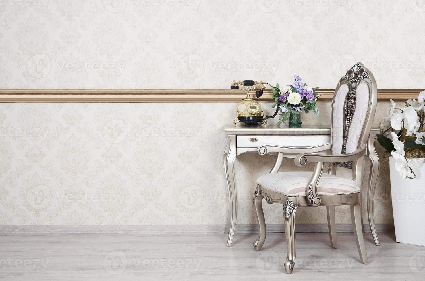 um fragmento de um interior retrô com uma cadeira e uma mesa na qual está localizado um telefone e um vaso de flores foto