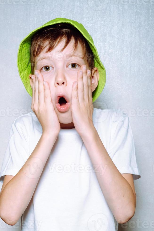 retrato de um menino surpreso em um chapéu panamá verde claro, sobre um fundo branco foto