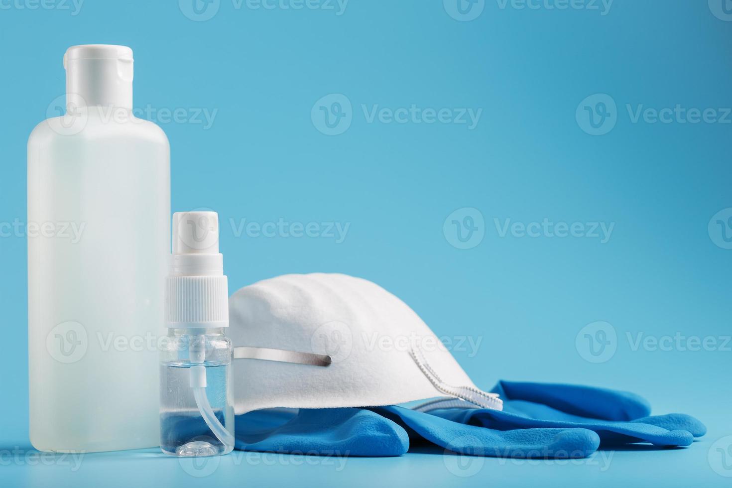 kit de proteção antivírus em fundo azul, máscara, luvas de borracha, frascos de desinfetante para as mãos, gel anti-séptico. foto