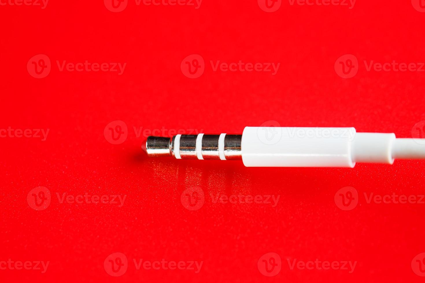 conector branco aux cabo branco em um fundo vermelho foto