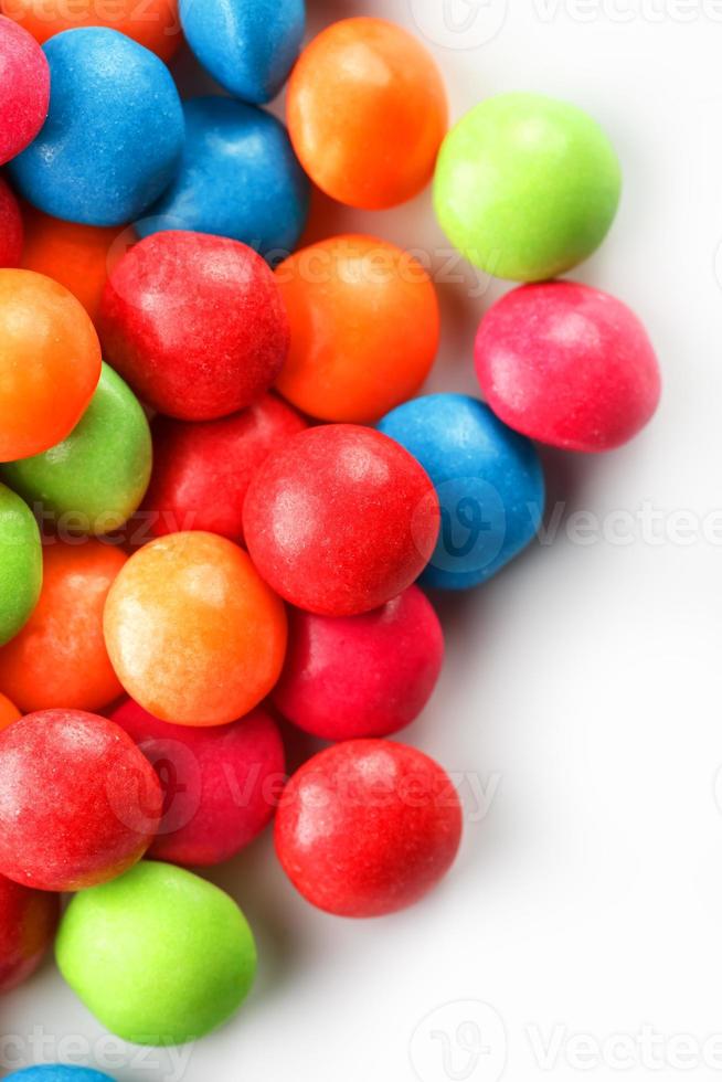 um arco-íris de cor de close-up de doces multicoloridos, drageia de esmalte multicolorida sobre um fundo branco foto