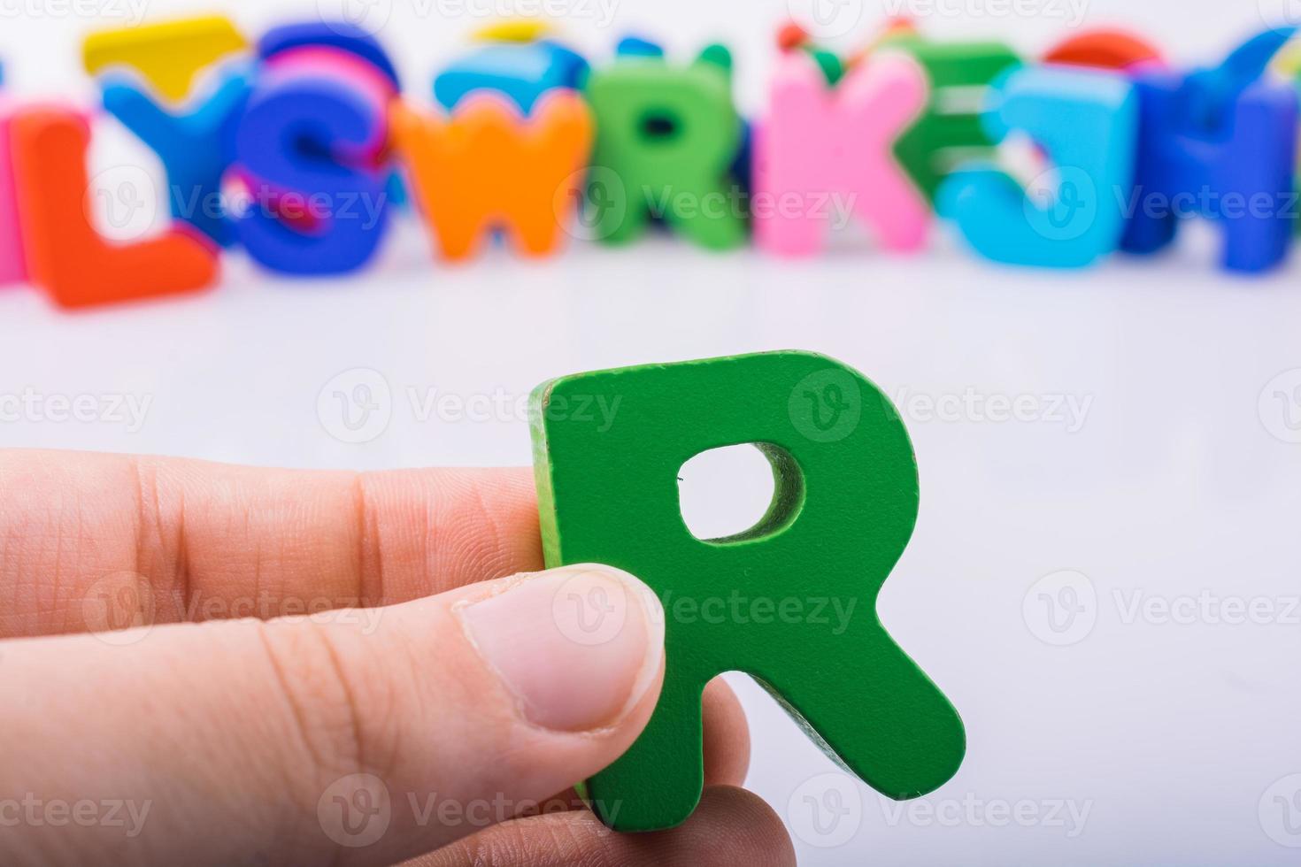 mão segurando a letra cubo r do alfabeto foto