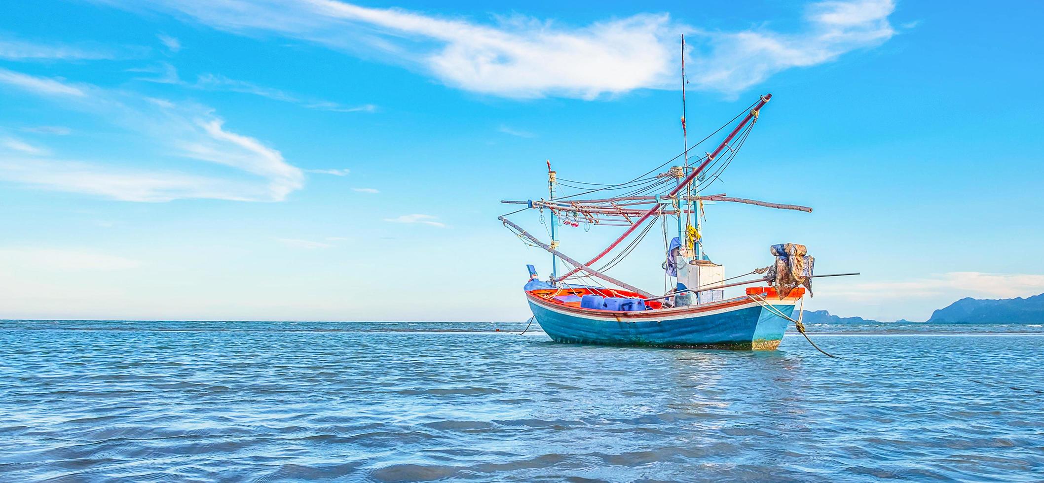 uma vista de um barco de pesca atracado à beira-mar pela manhã com um lindo mar azul e céu. foto