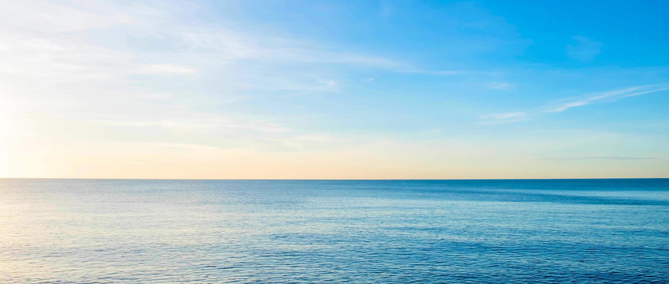 a vista do mar de manhã com os raios dourados do sol brilhando no mar no verão foto