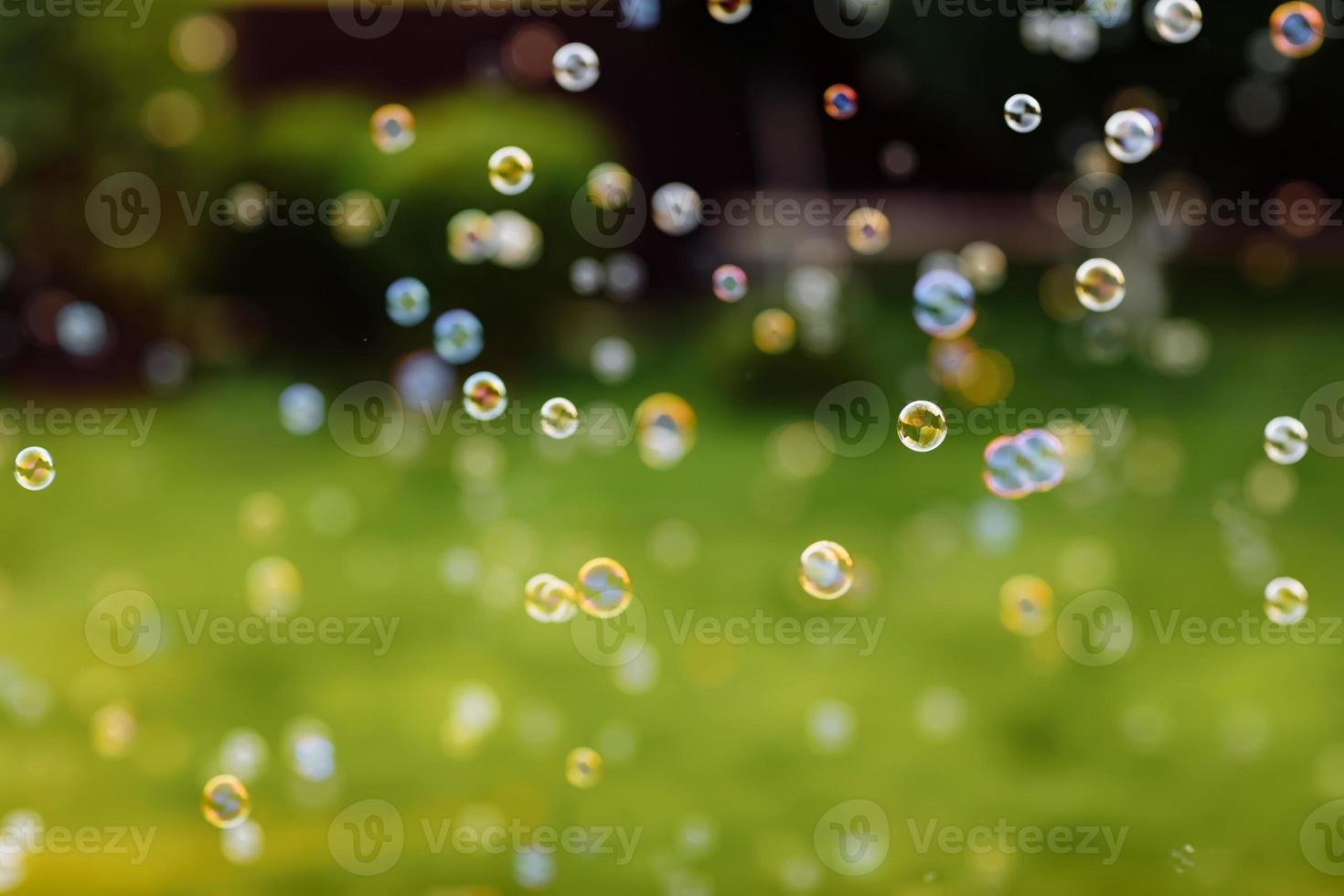 bolhas de sabão brilhantes no fundo abstrato verde natural de verão. muitas bolhas de sabão voando em dia ensolarado. primavera ou verão. símbolo da infância, pureza, ecologia. foto