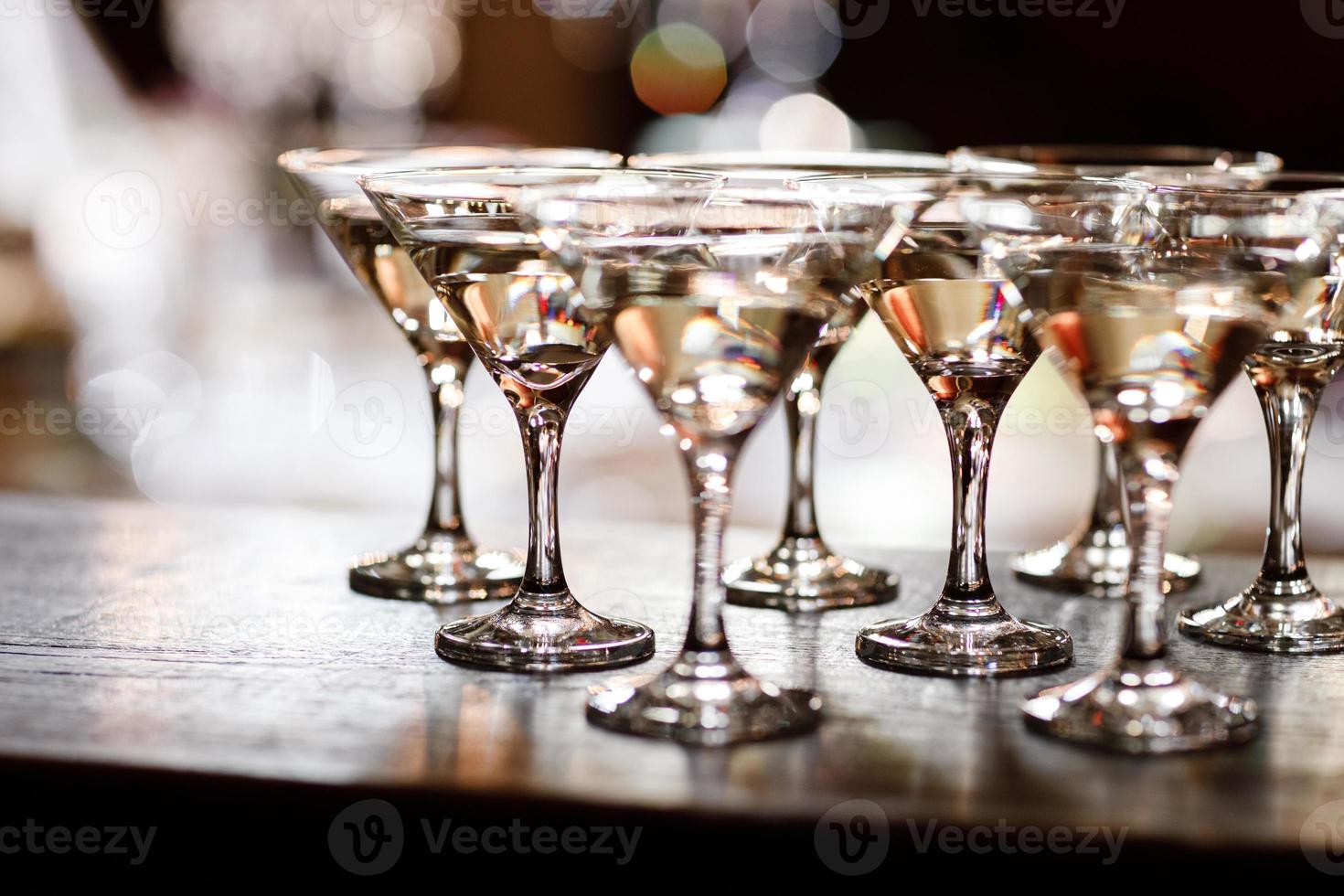 copos de martini na frente de ouro bokeh de fundo. bebida de coquetel de luxo no bar do restaurante com borrão de luzes noturnas. festa de celebração de bebidas elegantes para ano novo, natal, dia dos namorados. foto